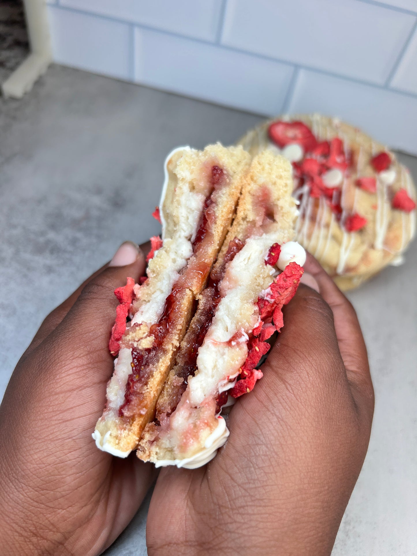 Hand holding a layered gourmet cookie dessert with red and white chocolate toppings
