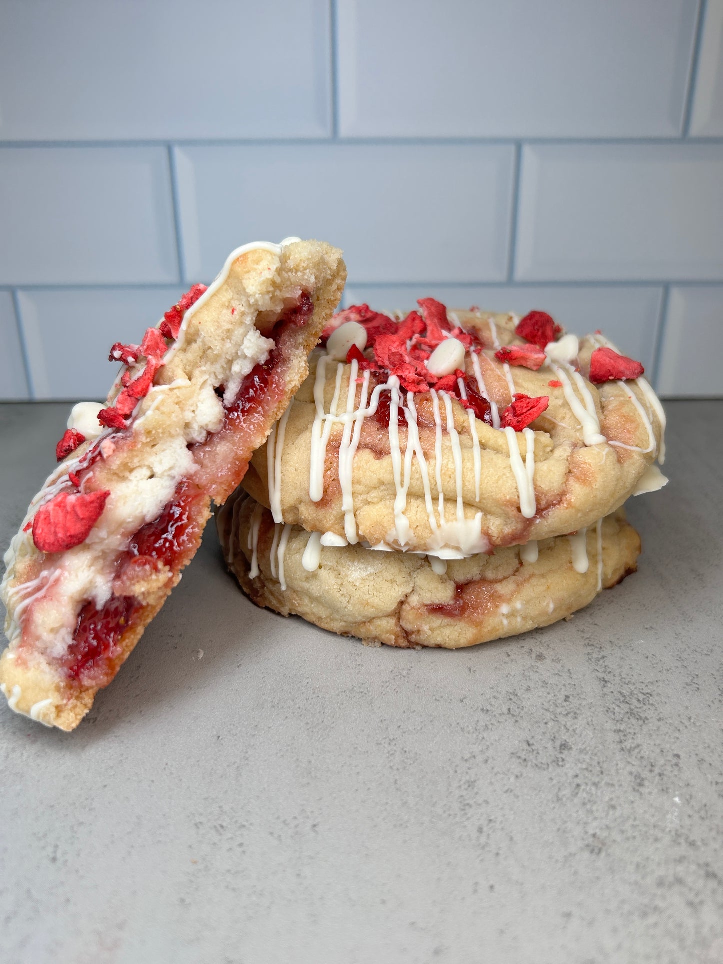 Strawberry cheesecake cookie with one piece missing, leaning against a wall.
